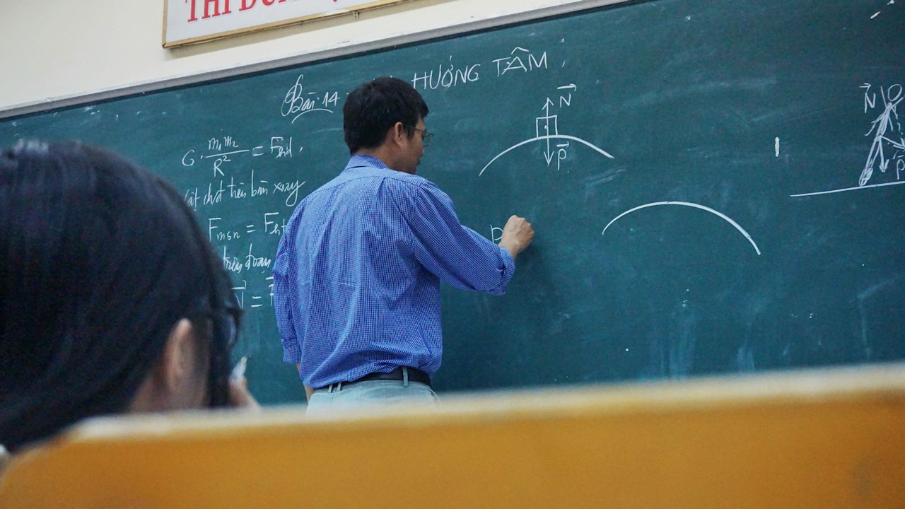 מורה מסביר תרגילי פיזיקה על לוח בכיתה – צילום המחשה לעבודה בהוראה בחו״ל