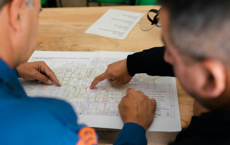 שני אנשי צוות הנדסה בודקים שרטוטים טכניים במפעל – צילום המחשה לעבודה כמהנדס בחו״ל